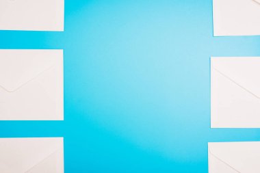 Ortasında boşluk olan beyaz kağıt zarflarla mavi arkaplan.