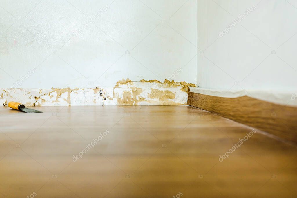 Renovation work on the baseboards and walls of a room.