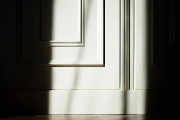 Shadows and sun rays outline a  white wooden door with a skilled carpenter.