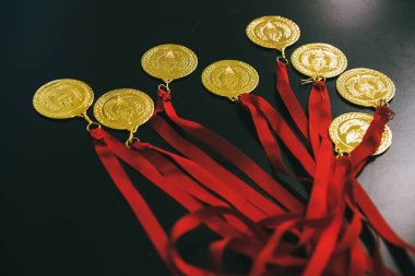 Kazananları ödüllendirmek için siyah bir masada altın madalyalar..