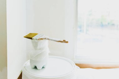 Tadilat altındaki bir odada bir kova beyaz boya ve fırça..