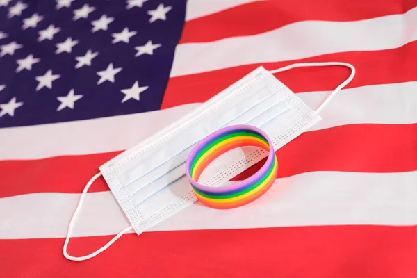 Disposable surgical mask and armband with lgbt colors on the background of the American flag.
