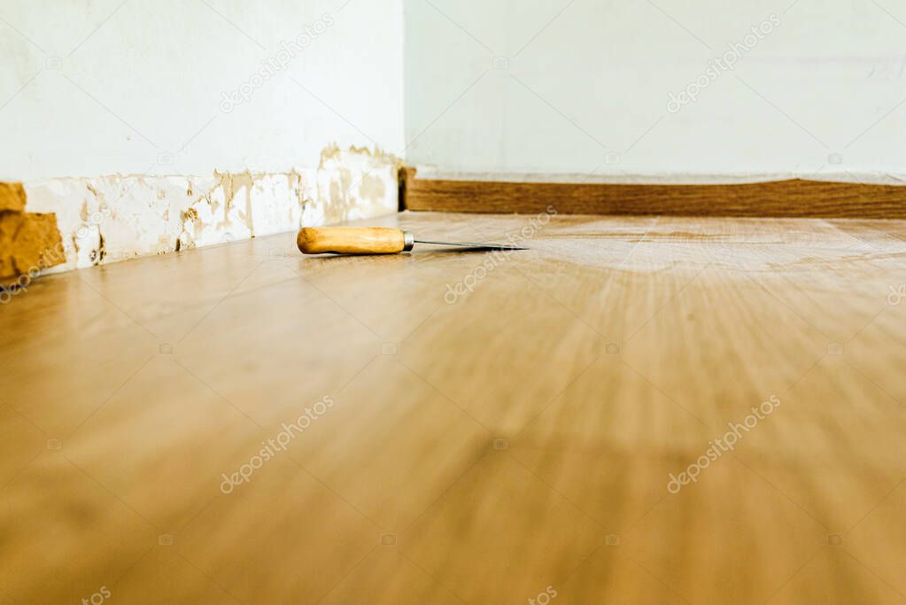 Renovation work on the baseboards and walls of a room.