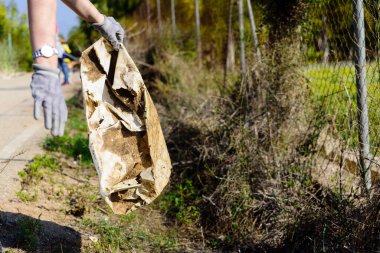 Doğada terk edilmiş çöpleri ve plastikleri toplayan bir gönüllü..