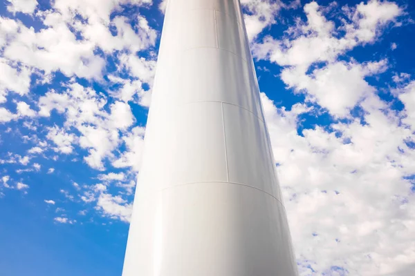 Thick metallic white pipe in vertical position as base of a tower, isolated on blue sky background.