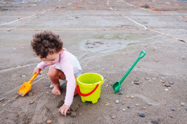 Bir bebek, salgından sonraki yeni normallik döneminde plajda oynamaktan hoşlanır..