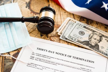 Amerikan bayrağının arka planında, dolar ve hijyenik maskelerle birlikte 30 günlük fesih bildirimi belgesi.