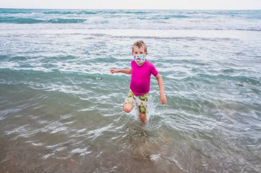 Tatilde virüslere karşı koruyucu maske takan bir çocuğun portresi..