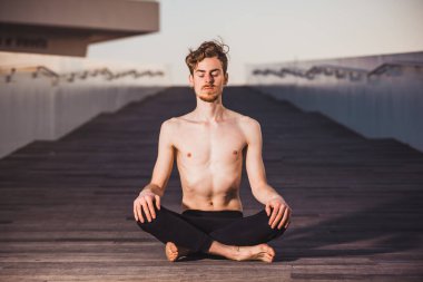 Genç adam şehrin stresinden kurtulmak ve egzersiz yapmak için yoga yapıyor..