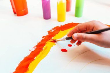 Genç çocuk, kağıt bir tuvalde fırçayla resim yapmayı öğreniyor. Hayal gücünün parlak renklerle çalkalanmasına izin veriyor..