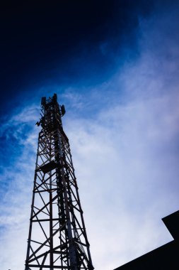 Uzun, modern bir iletişim kulesi bir şehre telekomünikasyon hizmeti sunuyor, mavi arka planda negatif alan..