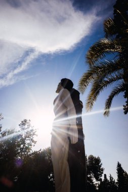 Silhouette against the sun of a religious sculpture. clipart