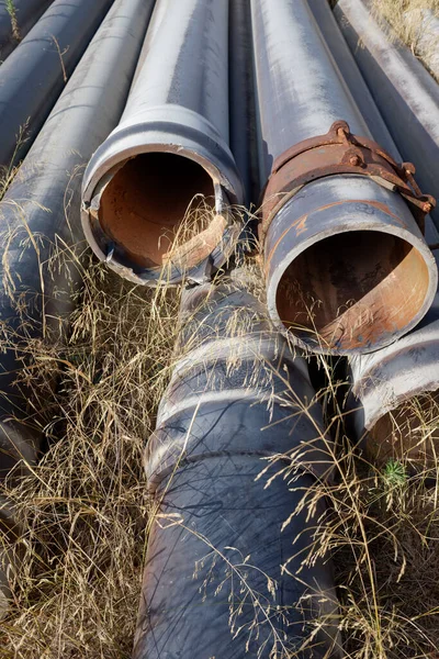 Old discarded pipes rusting in the open air abandoned in a field.