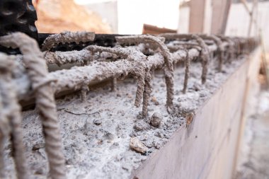 Detail of steel bars inside cement for the reinforced concrete of the foundations of a wall of a building under construction, with unfocused background. clipart