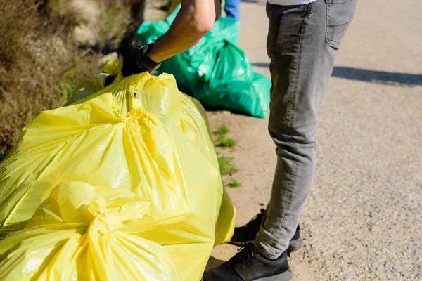 ボランティアは汚染された自然環境からプラスチックごみを収集し 袋に入れて保管します — ストック写真