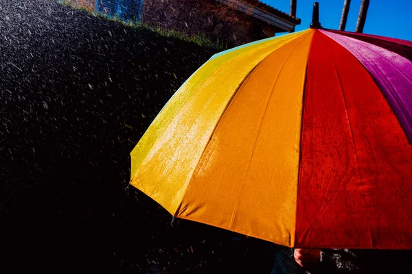 Rain on a warm-toned umbrella lit by the sun, isolated on black background with copy space.