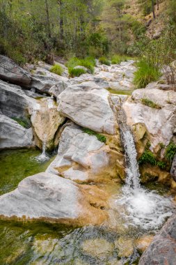 Nehir yatağındaki parlak kayaların üzerine dökülen su seli..