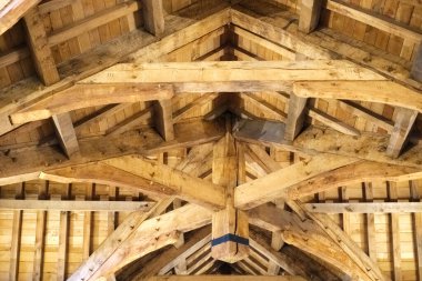 Bu detaylı görüntü, kırsal bir iç çatının karmaşık ahşap kiriş yapısını yakalıyor, sıcaklığı ve işçiliği vurguluyor, mimari meraklıları ve inşaatçılar için mükemmel..