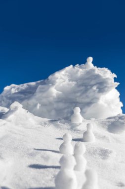 Kardan adamlar buzlu bir dağın zirvesine tırmanıyor, kış mevsimi konsepti