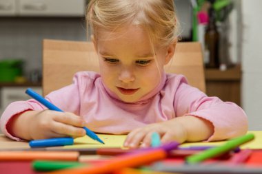 Bir sürü pastel boyası olan güzel sarışın bir kızın portresi.