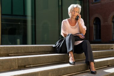 Çekici yaşlı iş kadını akıllı telefonuyla arıyor. 