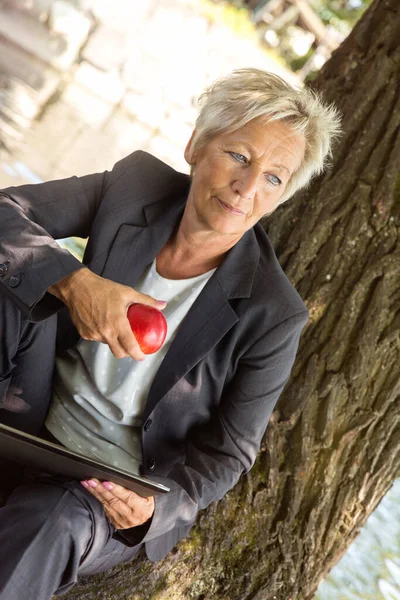 女商人坐在树上吃苹果 这是健康营养的概念 — 图库照片