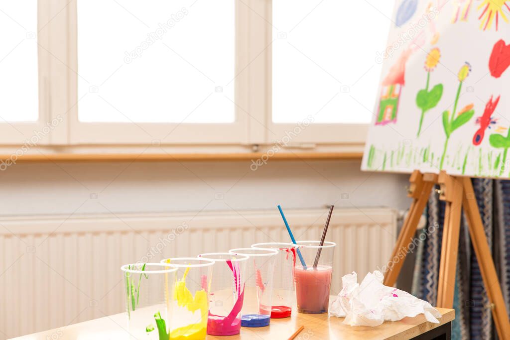 A canvas with color cups and brushes in the front