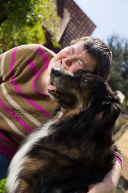 Zihinsel engelli bir kadın köpeğe sarılıyor.