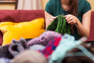 Arka planda kadın olan örgü malzemeleri ve yün yakın plan.