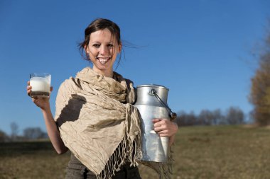 Süt sürahisi ve süt dolu bardakla gülümseyen güzel kadın
