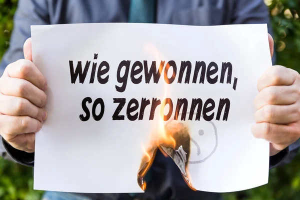 Geschäftsmann Hält Brennendes Papier Mit Deutschem Text Wie Gewonnen Zerronnen — Stockfoto