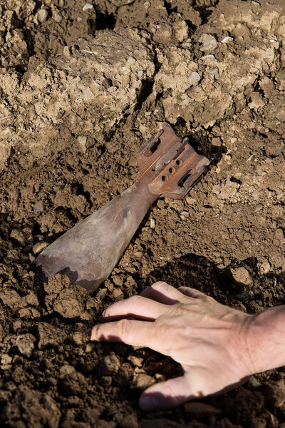 close up from a hand and a old grenade in the soil