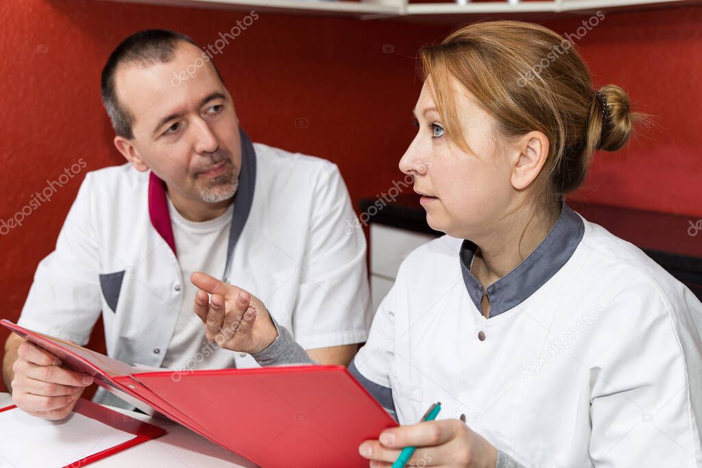 two doctors having a conversation, watching some documents