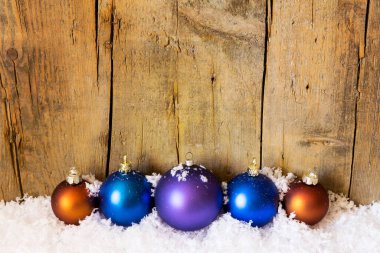 Tahta duvarın önünde Xmas topları olan bir kartpostal.