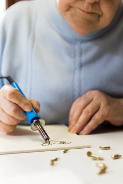 Yetişkin bir kadın sanat terapisi olarak odunları yakıyor.