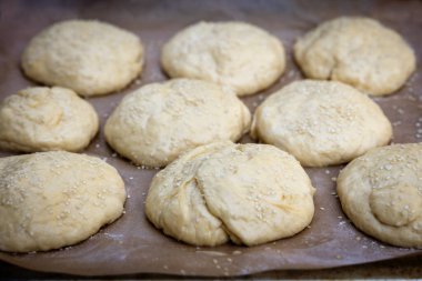 Hamur işi kağıt üzerinde, çörekler pişirmeye hazır.