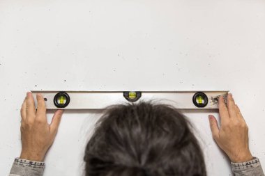 Adam duvarda baloncuk seviyesinde tutuyor, kopyalanmış boşluk