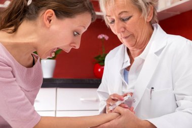 İğne fobisi olan genç bir bayan hasta bağırıyor çünkü iğne olacak.