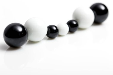 Beyaz arkaplanda farklı boyutlarda siyah ve beyaz misketler