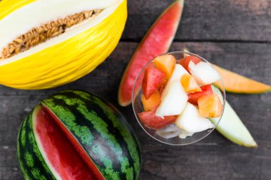 Meyve salatasının tepesinde çeşitli kavun dilimleri ve kanarya ve karpuz var.