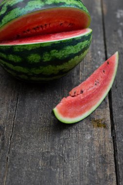 Koyu renkli ahşap bir masada karpuz, bir parça karpuz.