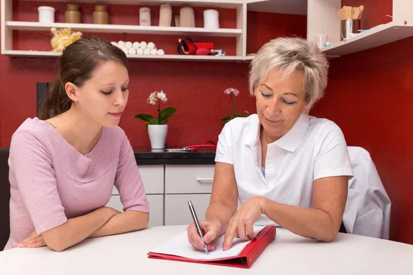 Verzorger Met Jonge Vrouw Zitten Aan Een Tafel Praten Documenten — Stockfoto