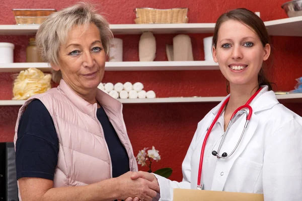 Jonge Vrouwelijke Arts Geven Een Oudere Patiënt Een Handdruk Rood — Stockfoto