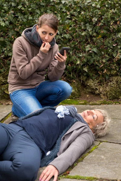 Ung Kvinna Gör Ett Nödsamtal Eftersom Äldre Vuxen Ligger Marken — Stockfoto