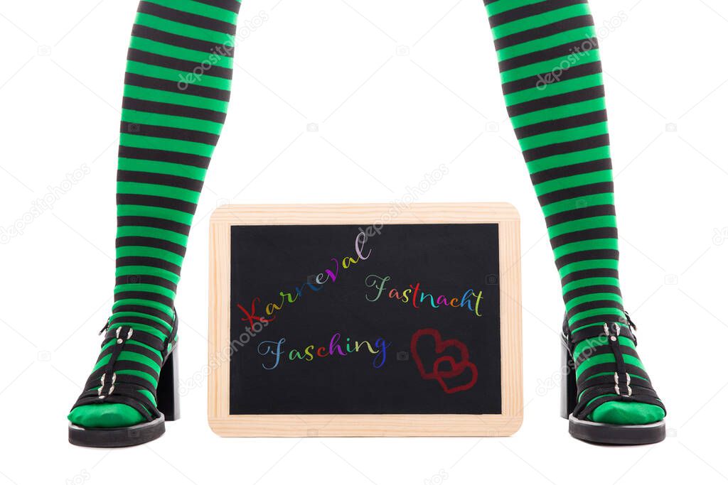 witch or goblins green and black striped legs slate with german words for carnival, isolated on white