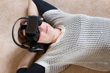 downview of a woman, wearing vr glasses, laying on the ground clipart