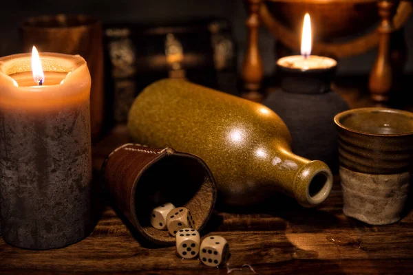 中世纪的桌子 有蜡烛 一个旧瓶子 一个杯子和木制骰子 概念游戏派对 — 图库照片