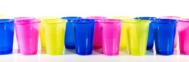 Bir sürü renkli plastik bardak, beyaz bardakların önünde dizilmiş.