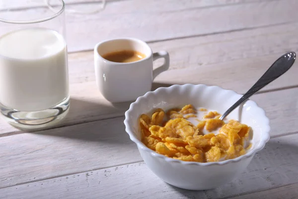 Καλαμπόκι νιφάδες δημητριακών σε ένα μπολ, γυαλί με γάλα και καπάκι με καφέ espresso. Πρωινό το πρωί. — Φωτογραφία Αρχείου