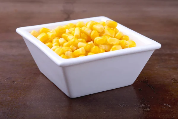 Sweet canned corn in white bowl. Ingredients for salad. Selective focus.